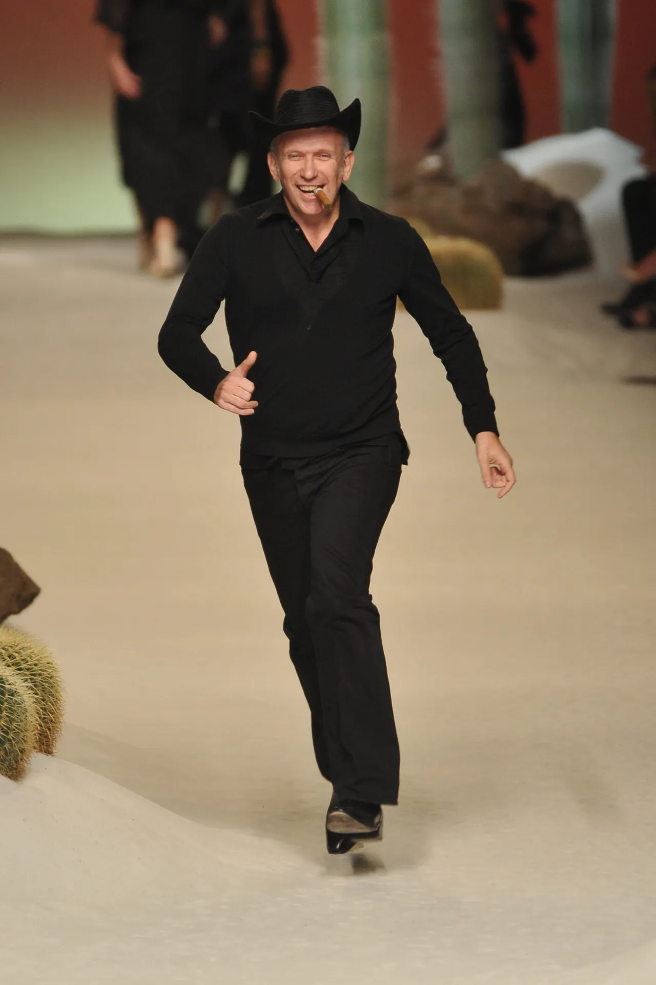 Designer walking a runway in black with a hat and cigar