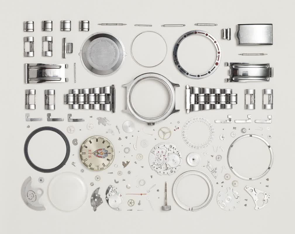 Exploded view of a disassembled watch — every component laid out with precision on a neutral surface